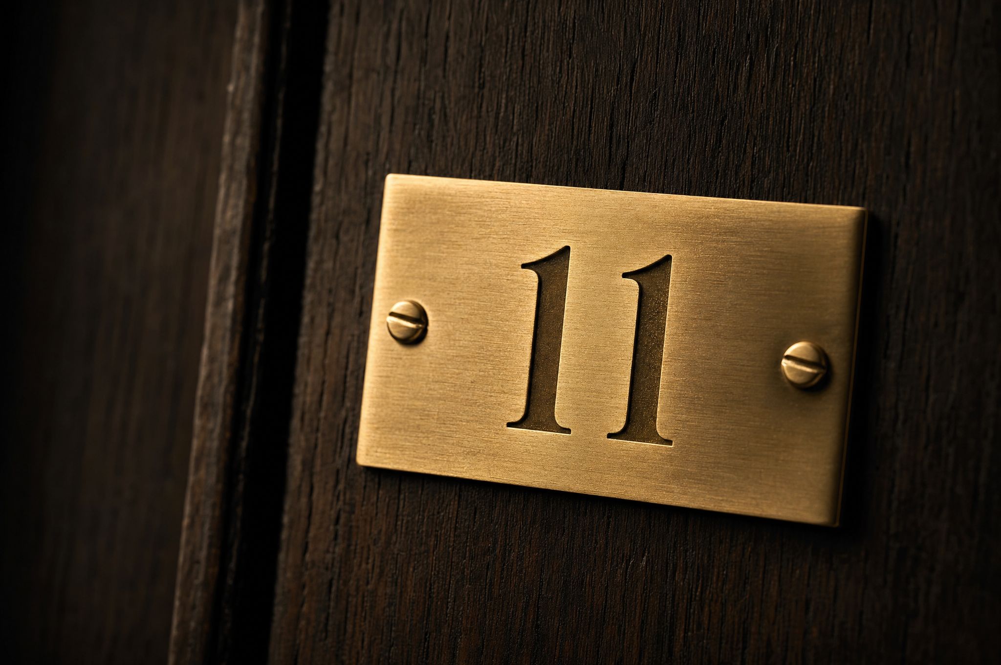 The No. 11 brass plate, fixed to a dark timber door